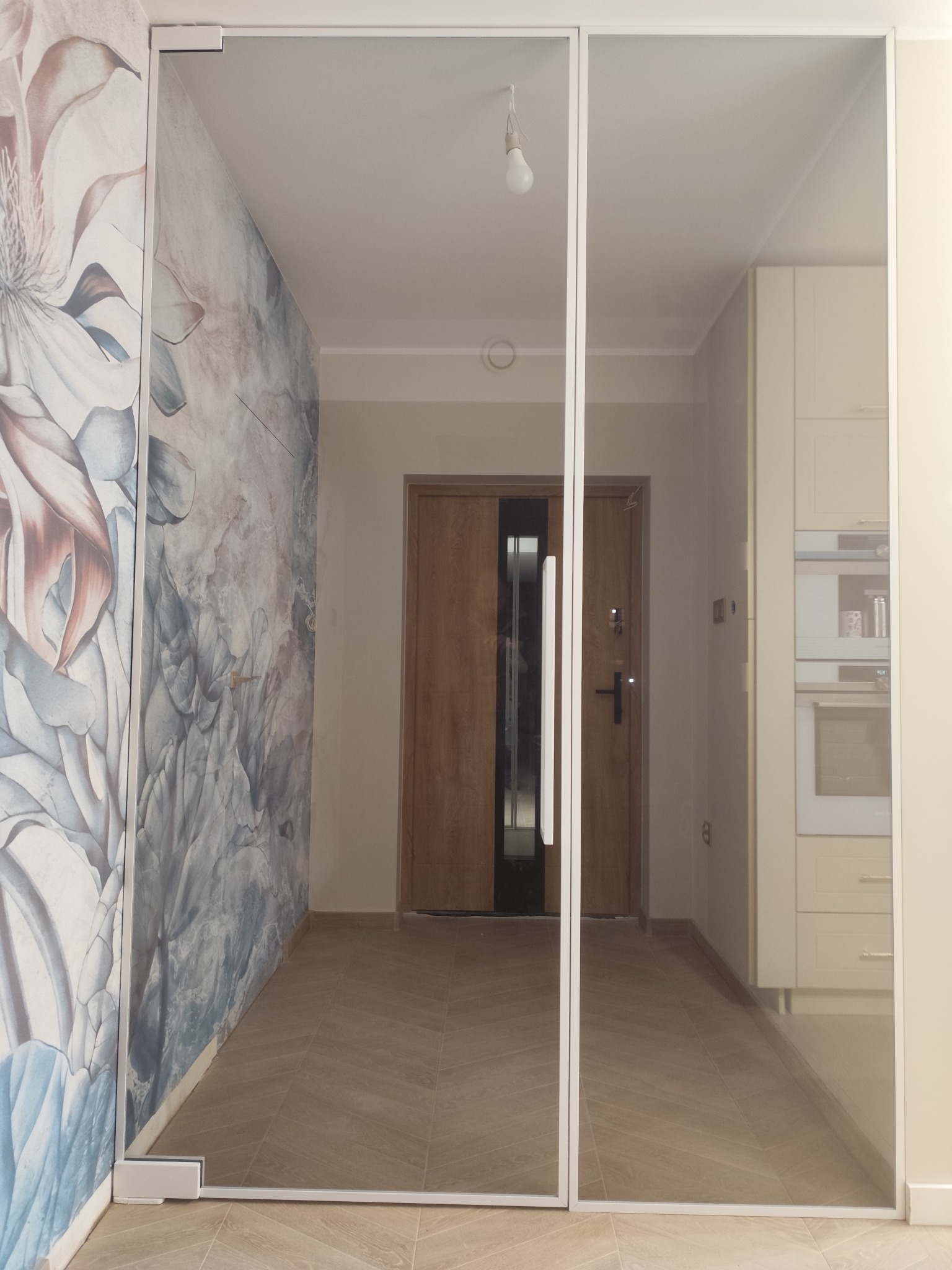 Drzwi wahadłowe ze stałym panelem szklanym w białej ramce.