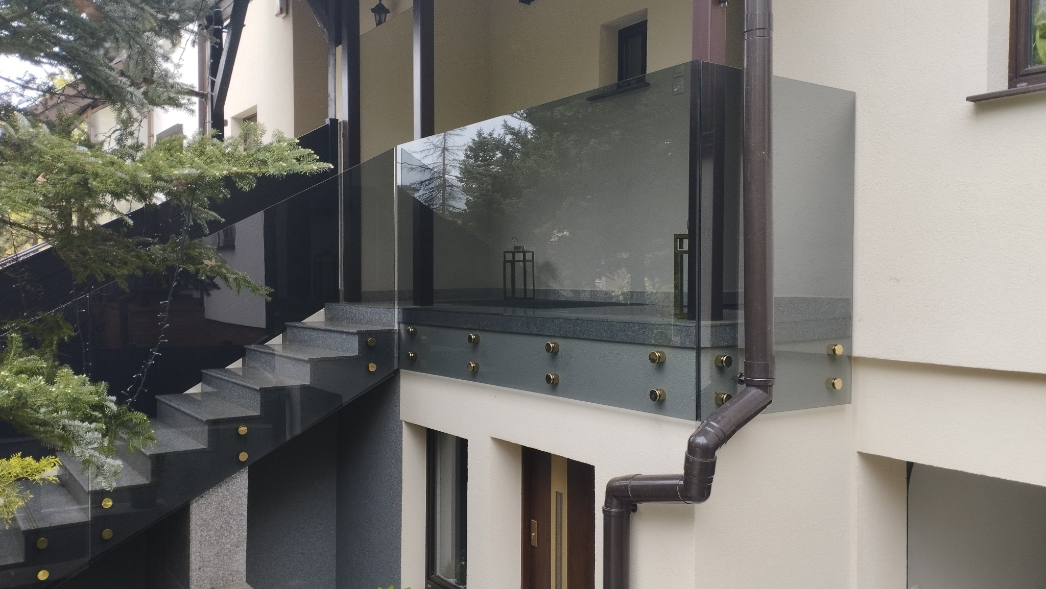 Balustrada szklana samonośna na ganku domu - szkło grafitowe ze złotymi mocowaniami.