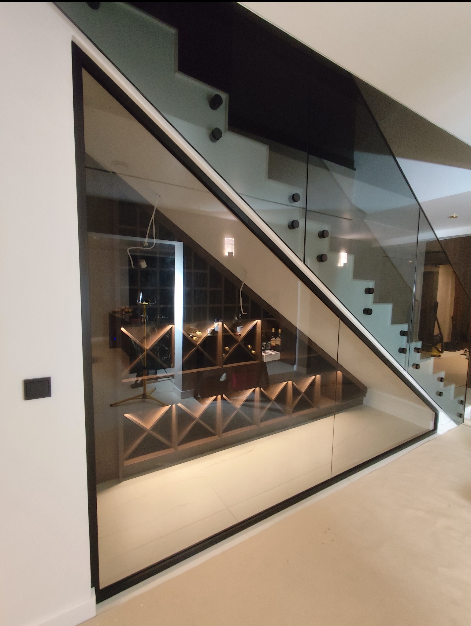 Całoszklana zabudowa wnęki pod schodami z drzwiami w ościeżnicy z przymykiem magnetycznym - szkło grafitowe.