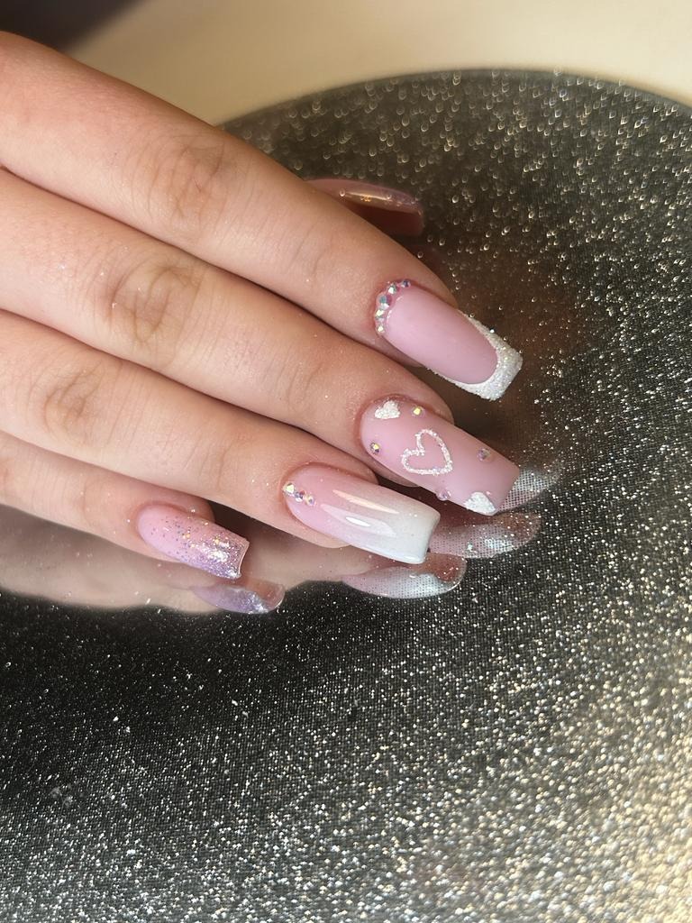 Delikatne, różowe paznokcie z motywem serca i srebrnymi zdobieniami, wykonane w Łodzi, na błyszczącym tle.