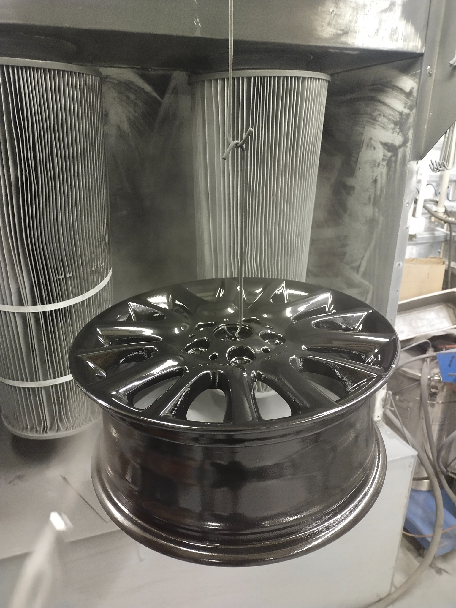 Aluminiowa felga samochodowa po procesie lakierowania proszkowego w kabinie lakierniczej z widocznymi filtrami