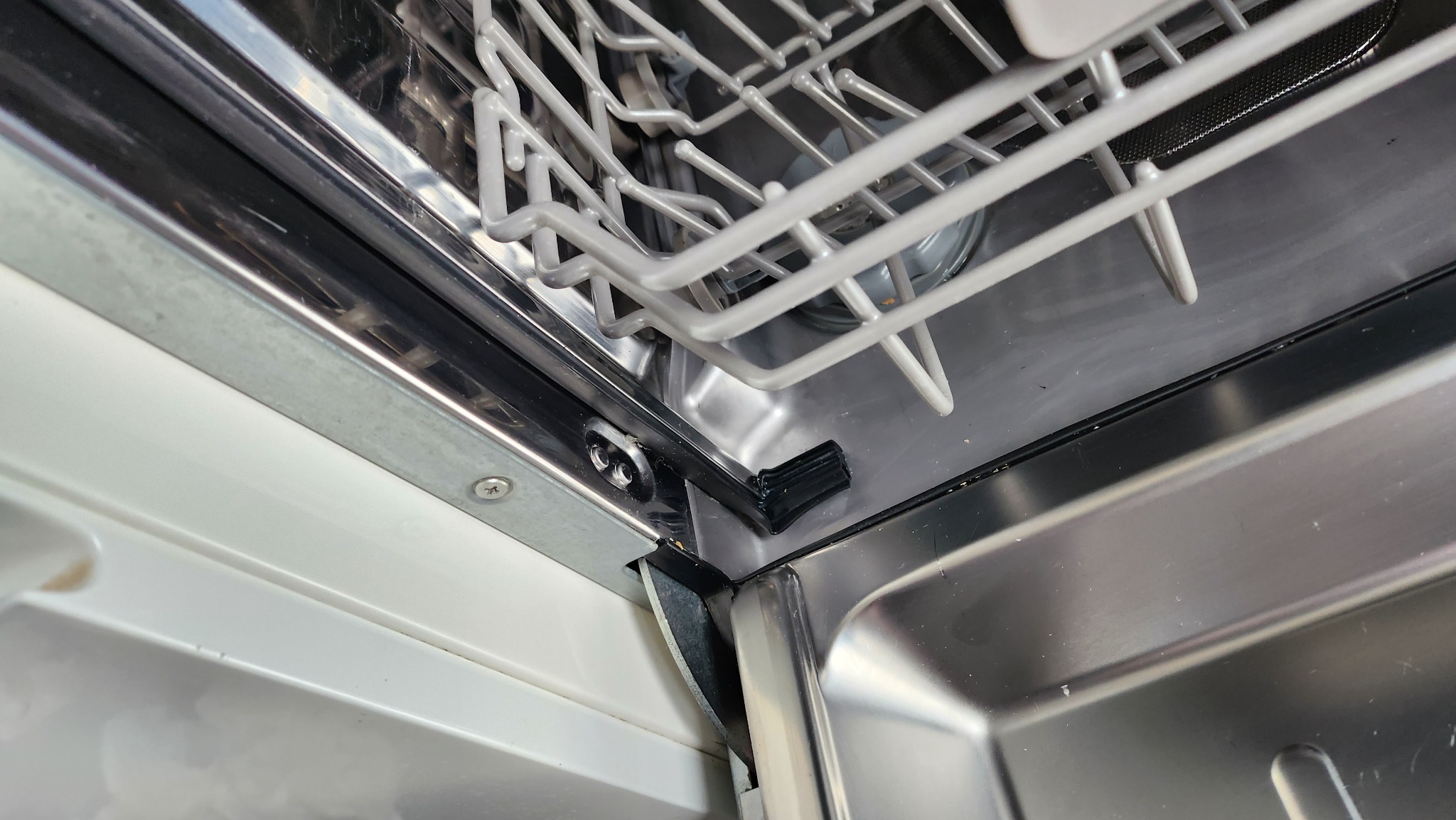 Wnętrze umytej zmywarki z widocznym koszem na naczynia i uszczelką w rogu komory.