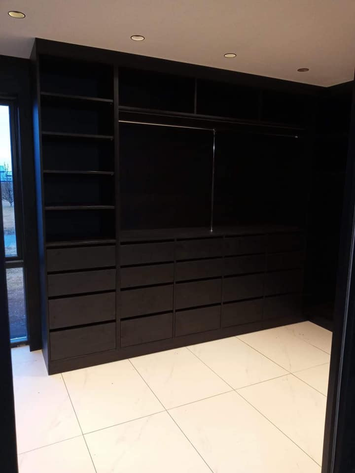 Czarna zabudowa garderoby z szufladami i półkami, widok z dołu, białe płytki podłogowe, zrealizowana w Gdańsku.