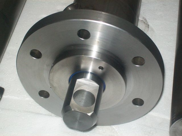 Metalowy element z kołnierzem i centralnym otworem o przekroju kwadratowym, widoczne ślady obróbki skrawaniem.