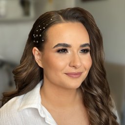 Glow District Dominika Rzymyszkiewicz - Portret kobiety z profesjonalnym makijażem i upięciem włosów z ozdobnymi spinkami, wykonanym w salonie w Warszawie. Uwagę przykuwają starannie podkreślone oczy.