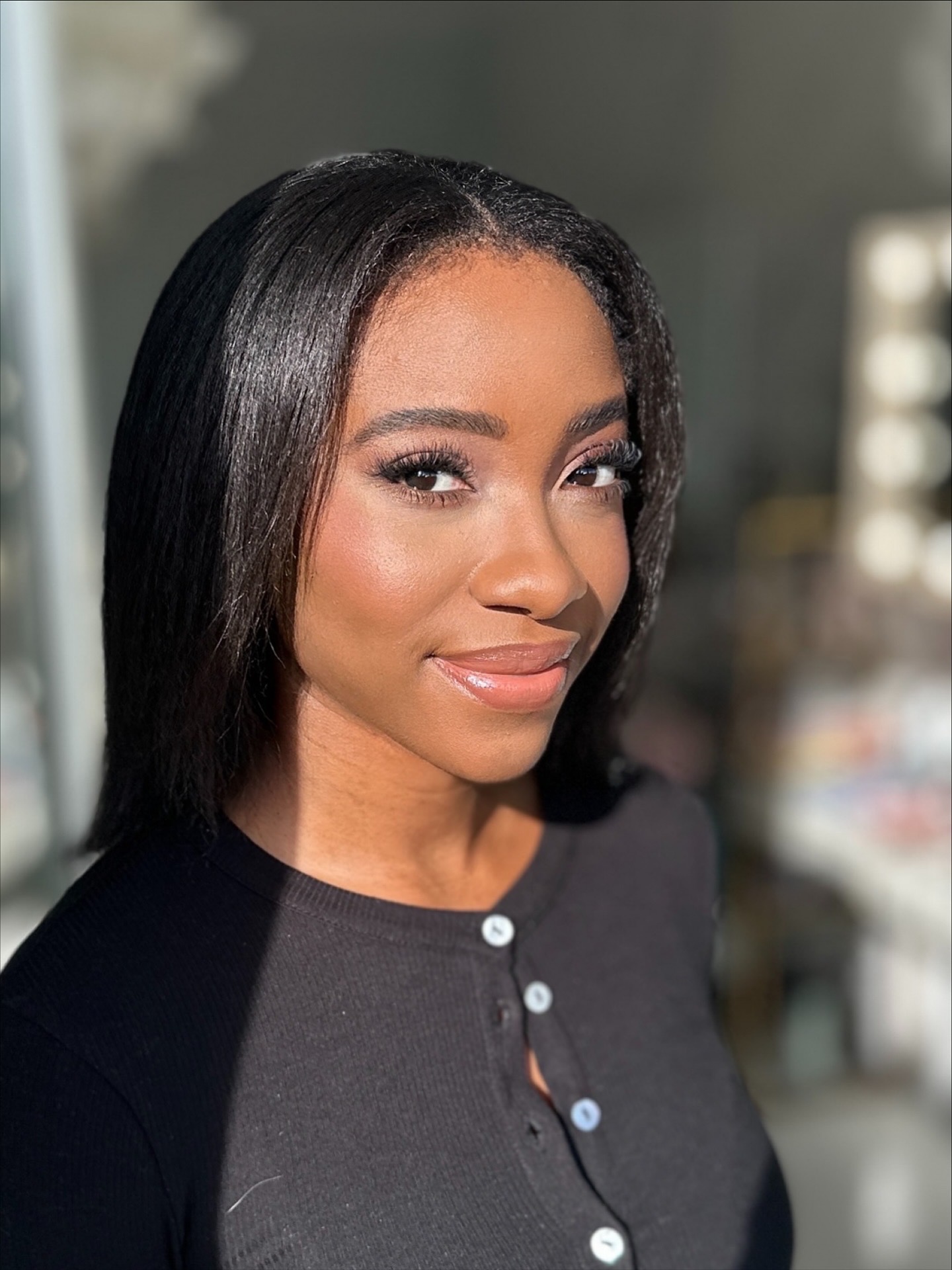 Portret młodej kobiety z delikatnym, naturalnym makijażem i gładkimi, ciemnymi włosami. Stonowane kolory i subtelne podkreślenie rysów twarzy.