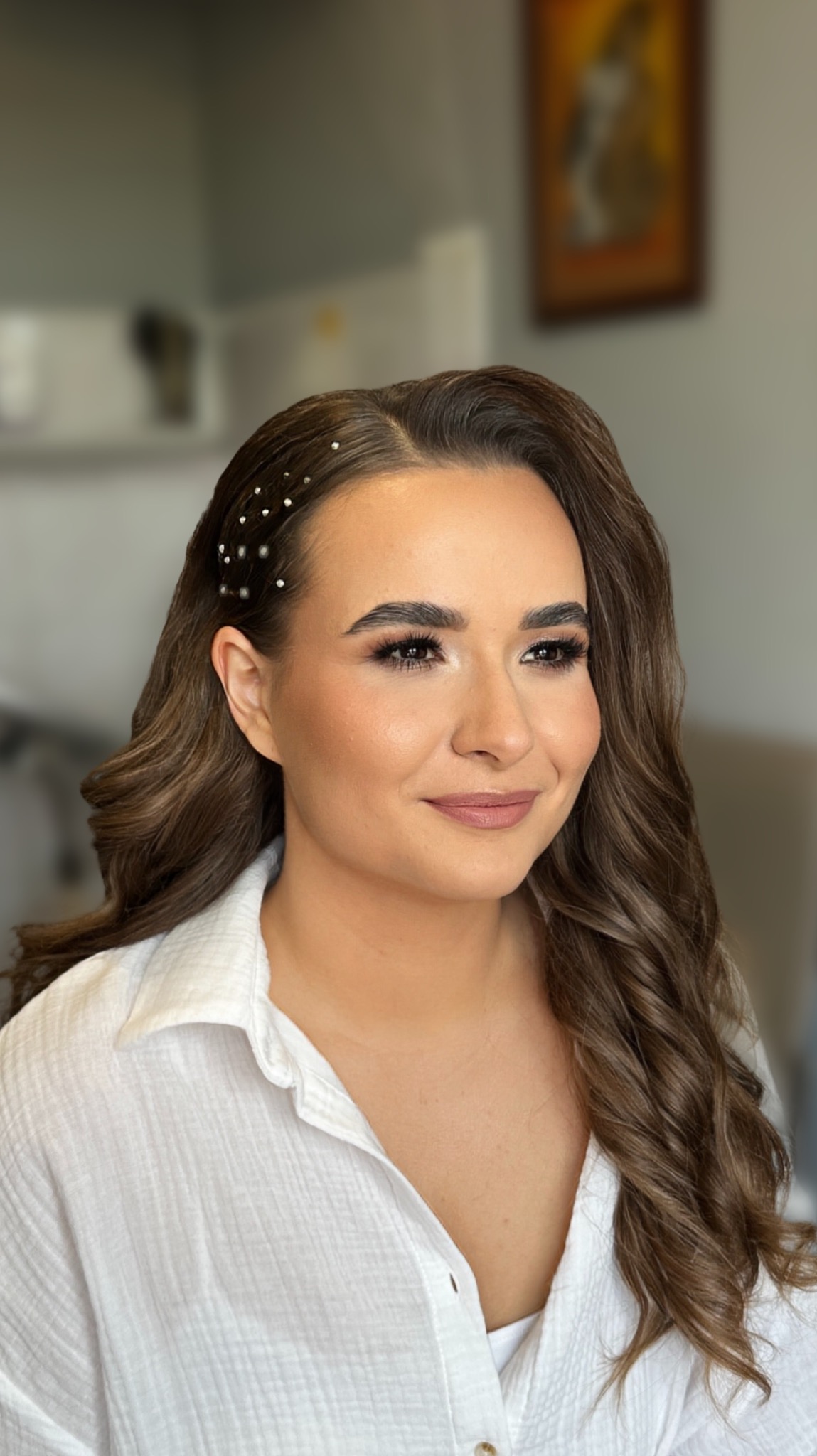 Portret kobiety z profesjonalnym makijażem i upięciem włosów z ozdobnymi spinkami, wykonanym w salonie w Warszawie. Uwagę przykuwają starannie podkreślone oczy.