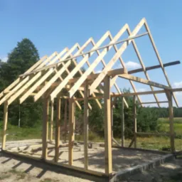 Konstrukcja drewniana altany w trakcie budowy, widoczny szkielet dachu i słupy na betonowej wylewce, w tle drzewa i błękitne niebo.