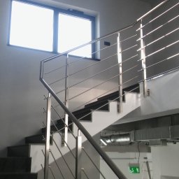 Volodymyr Mikhalets Amix balustrady nierdzewne - Nowoczesne schody z metalowymi poręczami i minimalistyczną balustradą ze stali nierdzewnej, widoczne elementy wentylacji pod schodami, jasne wnętrze z oknem na górze.