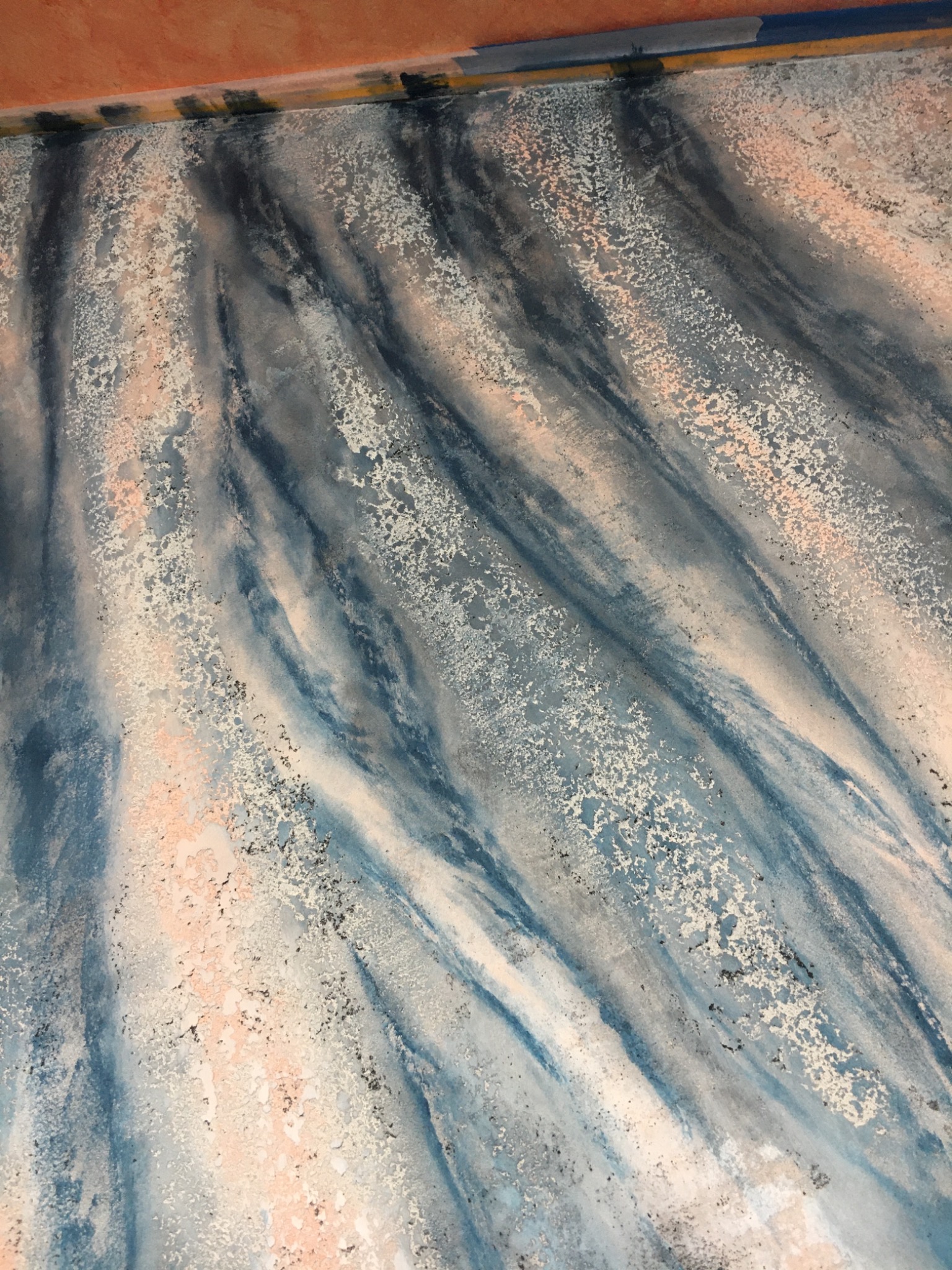 Dekoracyjna ściana z efektem marmuru w odcieniach błękitu, szarości i delikatnego różu, wykończona z widoczną strukturą i drobnymi, nieregularnymi plamkami.