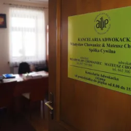 Tabliczka informacyjna Kancelarii Adwokackiej Władysław Chowaniec i Mateusz Chowaniec Spółka Cywilna umieszczona na drewnianych drzwiach wejściowych, widok na wnętrze biura z biurkami i krzesłami...