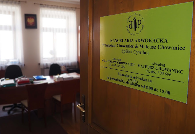 Tabliczka informacyjna Kancelarii Adwokackiej Władysław Chowaniec i Mateusz Chowaniec Spółka Cywilna umieszczona na drewnianych drzwiach wejściowych, widok na wnętrze biura z biurkami i krzesłami...