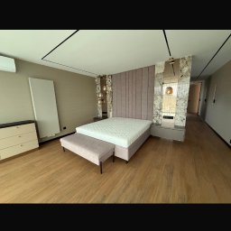 Baufirma Karpowicz - Nowoczesna sypialnia z łóżkiem kontynentalnym, tapicerowanym wezgłowiem i marmurowymi panelami. Parkiet na podłodze, minimalistyczne oświetlenie.