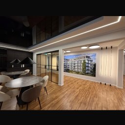 Baufirma Karpowicz - Nowoczesne wnętrze biurowe z drewnianą podłogą, szklanymi drzwiami i fototapetą przedstawiającą budynek mieszkalny. Minimalistyczny design, oświetlenie LED.