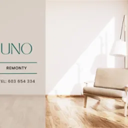 Jasne wnętrze z drewnianą podłogą, beżowym fotelem, lampą i logo firmy remontowej UNO na ścianie.