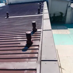 Brązowy dach z blachy trapezowej z odpowietrznikami, widok z góry, widoczne ślady po myciu lub czyszczeniu.