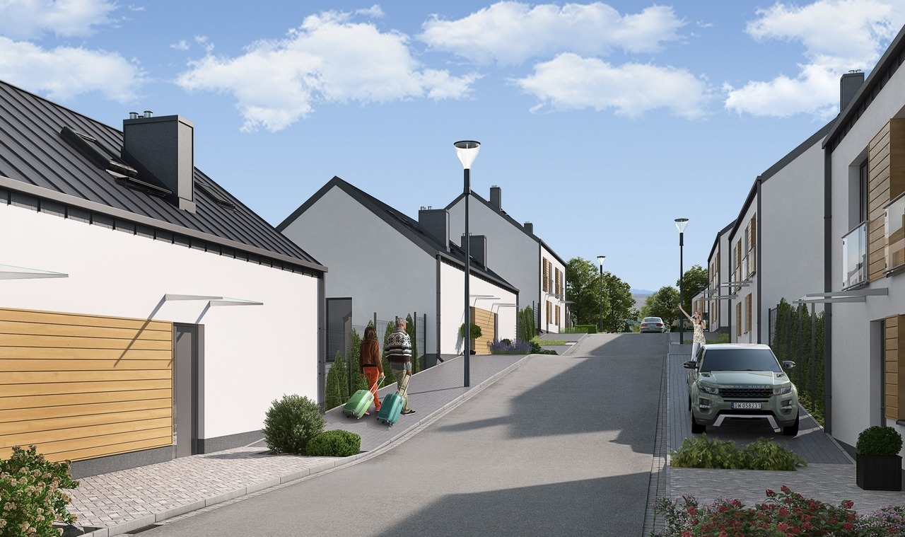 Osiedle nowych domów jednorodzinnych z szarymi dachami, nowoczesną elewacją i drewnianymi akcentami, dwie osoby ciągną walizki po chodniku, a kobieta macha do samochodu.