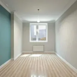 Puste, jasne pomieszczenie po remoncie z panelami podłogowymi, pomalowaną na turkusowo ścianą i białym grzejnikiem pod oknem z widokiem na miasto.