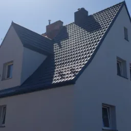 Dom z nowym, ciemnoszarym dachem z dachówki ceramicznej, widoczne kominy i okna, jasne elewacje, błękitne niebo w tle.