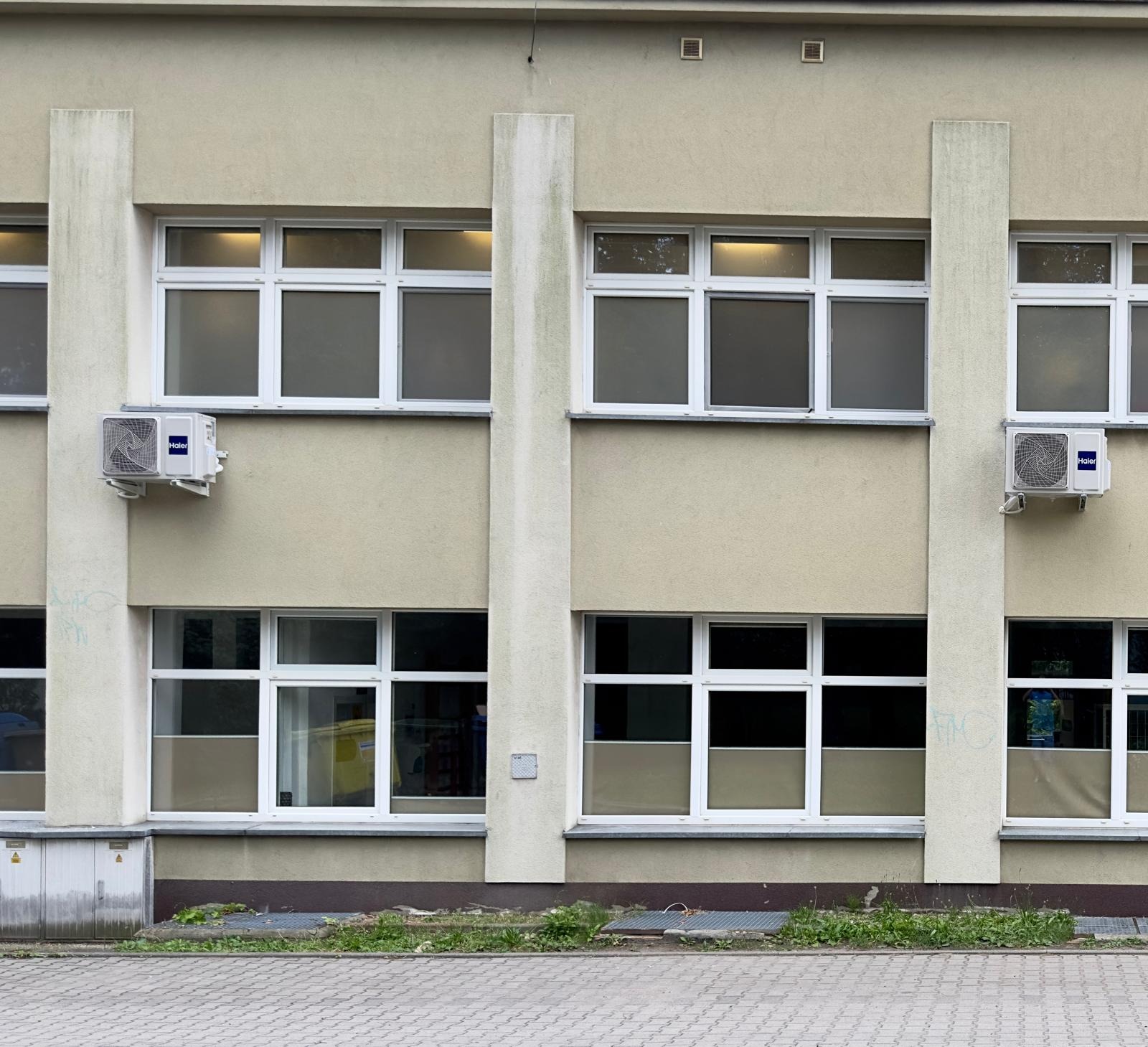 Elewacja budynku z oknami, na której zamontowano dwa klimatyzatory marki Haier.