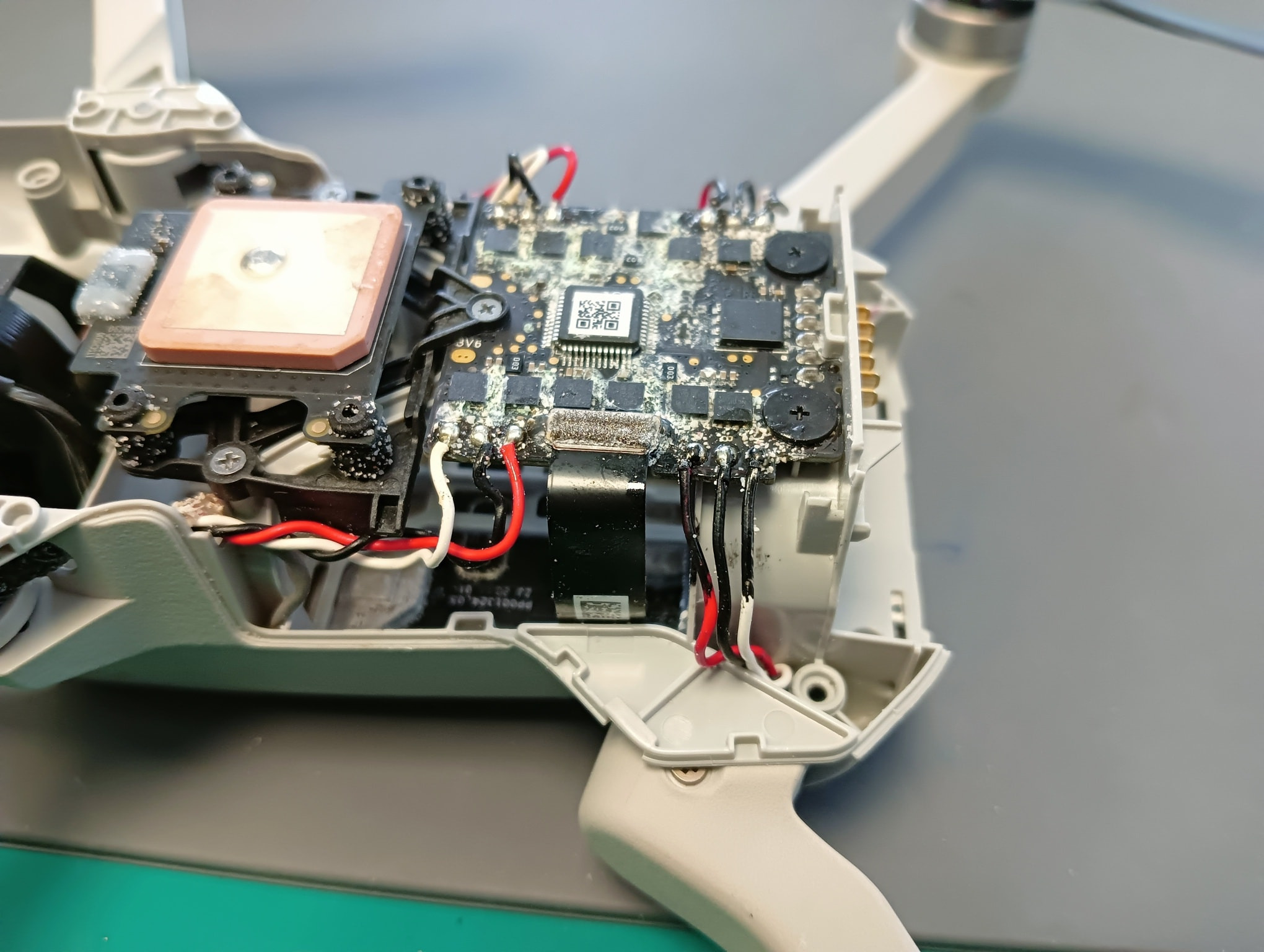 Wnętrze drona z widoczną płytą główną i elementami elektroniki pokrytymi białym osadem, prawdopodobnie po zalaniu.