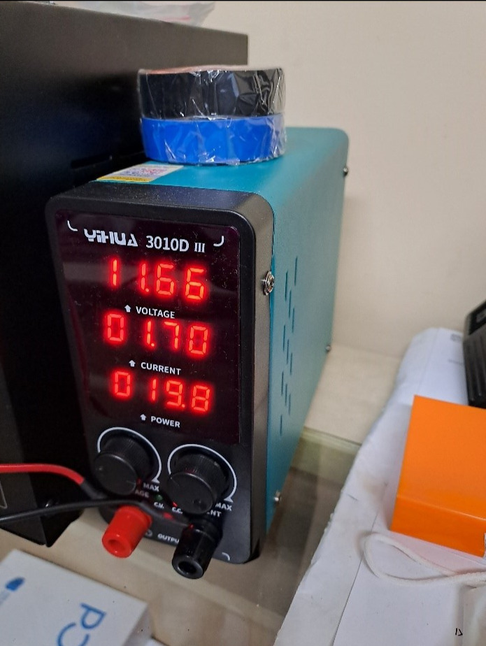 Zasilacz laboratoryjny YIHUA 3010D III z wyświetlaczem LED wskazującym napięcie, prąd i moc, obok leżące akcesoria i taśma izolacyjna na górze. Widok z bliska na panel sterowania.