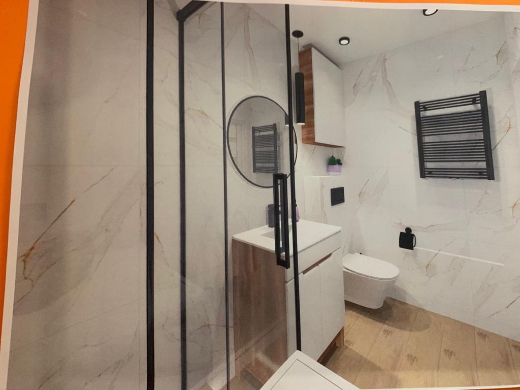 Wizualizacja łazienki z kabiną prysznicową typu walk-in z czarnymi profilami, okrągłym lustrem i grzejnikiem drabinkowym w kolorze czarnym na ścianie z marmurowym wzorem.