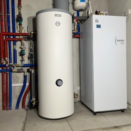 Sławomir Kondej Kompleksowe systemy dla domu - Biały zasobnik ciepłej wody NIBE i pompa ciepła Ecodan Mitsubishi z kompletną instalacją hydrauliczną w pomieszczeniu technicznym.