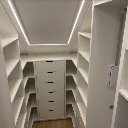 Włodarczyk Meble - Sandra Włodarczyk - Biała garderoba na wymiar z oświetleniem LED, widok z wnętrza. Szafki z szufladami i półkami, minimalistyczny design, jasne wnętrze, drewniana podłoga.