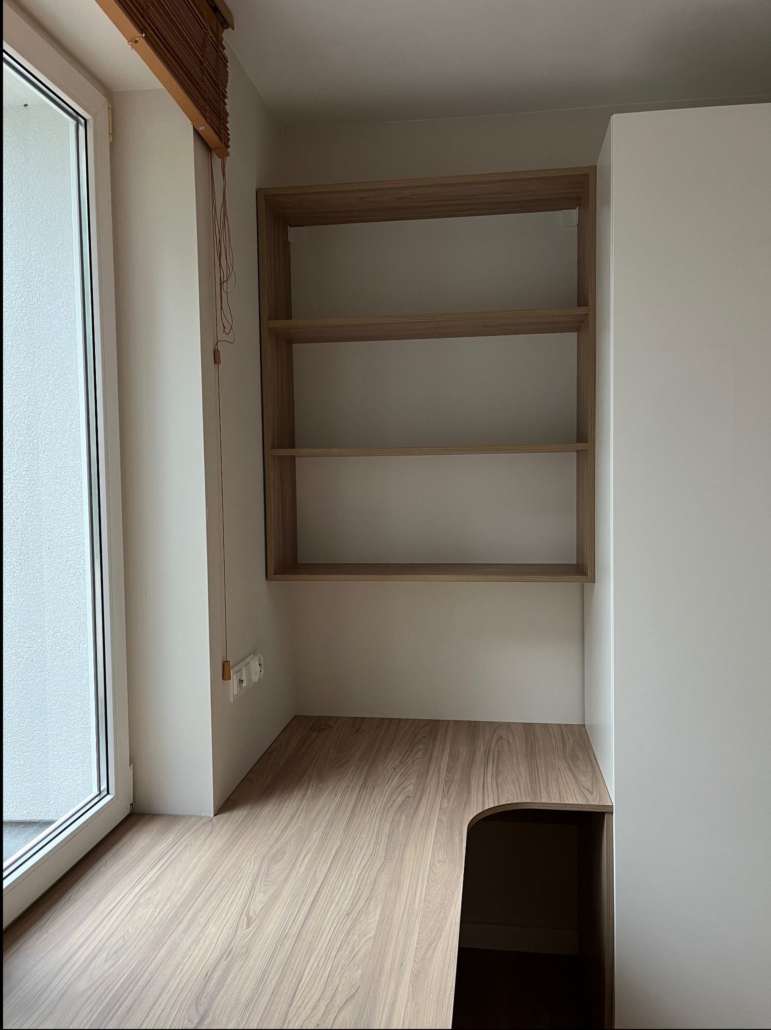 Drewniana szafa wnękowa z półkami i blatem w Ożarowie Mazowieckim, idealnie dopasowana do przestrzeni przy oknie. Minimalistyczny design, jasne kolory.