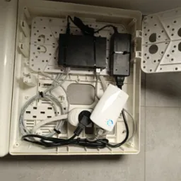 Wewnętrzna skrzynka z zainstalowanym routerem, switchem, zasilaczami i okablowaniem sieciowym, widoczne diody sygnalizacyjne routera.