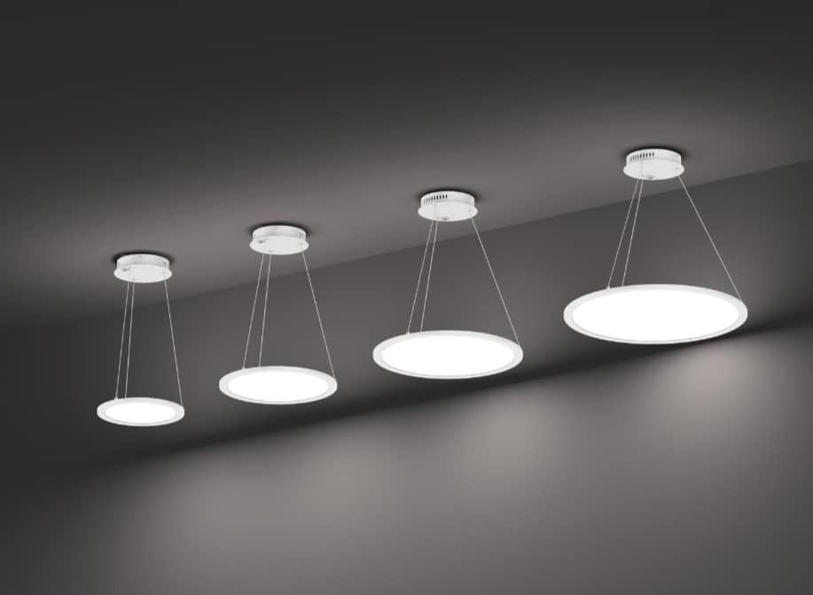 Cztery okrągłe lampy LED wiszące na cienkich linkach, różnej wielkości, ustawione w rzędzie na tle szarego sufitu.