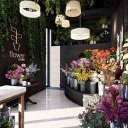 Wnętrze kwiaciarni z marmurowym blatem, różnorodnymi bukietami w metalowych wiaderkach, wiszącymi roślinami i logo kwiaciarni na ścianie.