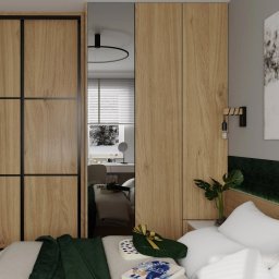 Zibinet - meble na wymiar - Nowoczesna szafa z przesuwnymi drzwiami w kolorze jasnego drewna z czarnymi ramami, wkomponowana w aranżację sypialni z lustrzanym panelem odbijającym toaletkę i oświetlenie.