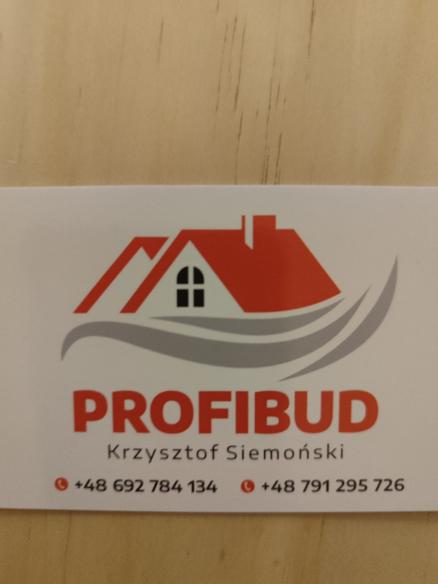 Wizytówka firmy budowlanej Profibud z logo przedstawiającym dom z czerwonym dachem i numerami telefonów.
