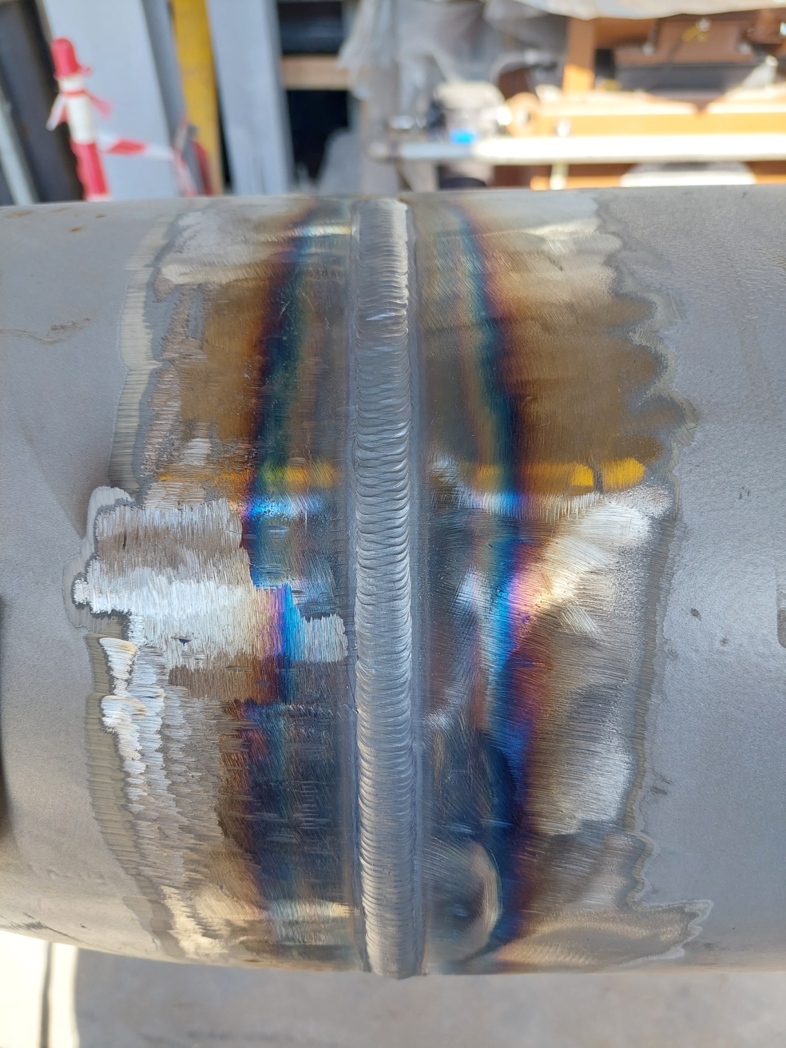 Spoina na rurze ze stali nierdzewnej z widocznymi kolorami utleniania, wskazującymi na temperaturę procesu