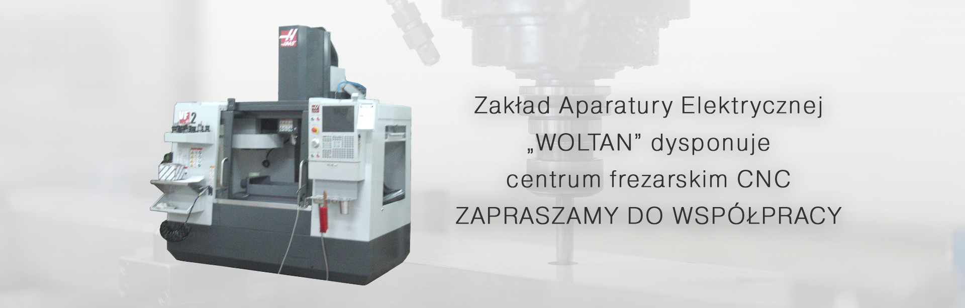 Szaro-biała frezarka CNC marki Haas, z widocznym panelem sterowania i logiem firmy, na rozmytym tle widoczny tekst 'Zakład Aparatury Elektrycznej WOLTAN dysponuje centrum frezarskim CNC ZAPRASZAMY...