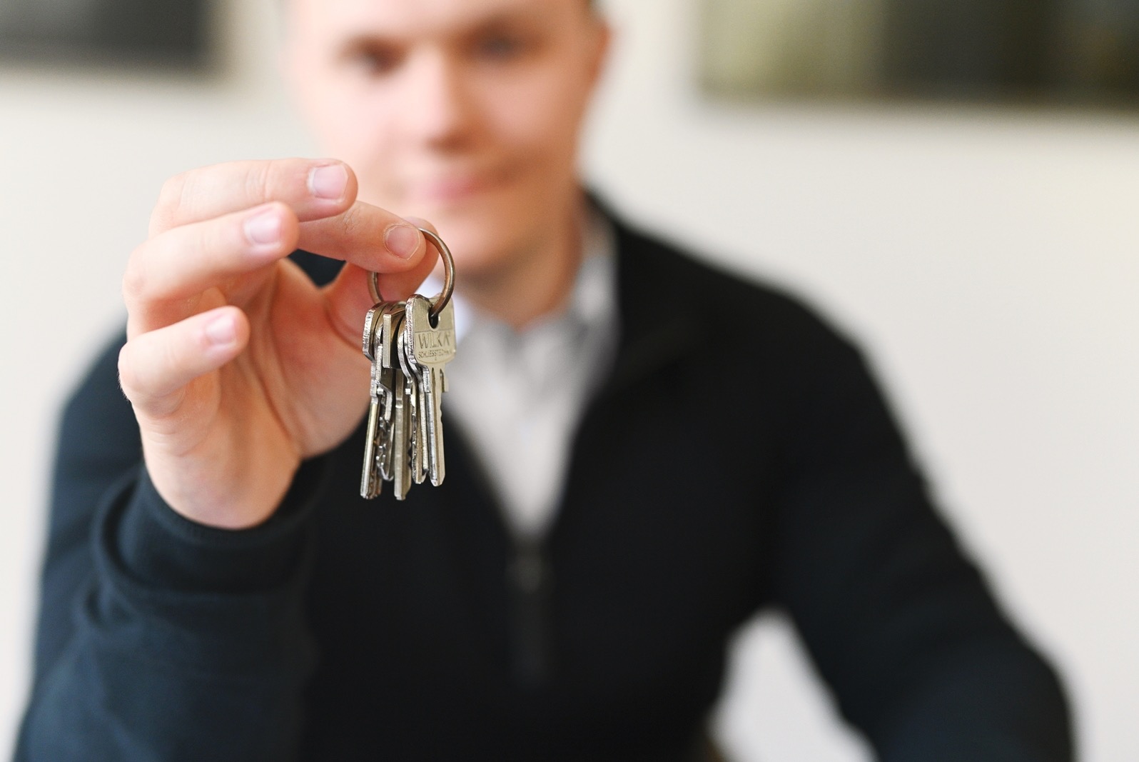Mężczyzna trzyma w dłoni pęk kluczy WILKA na metalowym kółku, lekko rozmazane tło