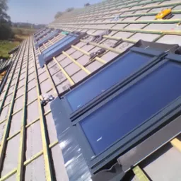 Montaż okien dachowych na nowym dachu z widoczną konstrukcją drewnianą i membraną dachową, w tle drzewa i zabudowania.