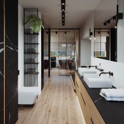 Inargo - Nowoczesna łazienka z dwoma białymi umywalkami na blacie z czarnego kamienia, drewniana podłoga i drzwi przesuwne z widokiem na salon.