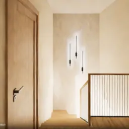 Wnętrze klatki schodowej w domu, z drewnianymi drzwiami po bokach, minimalistycznymi lampami na ścianie i drewnianą balustradą schodów.