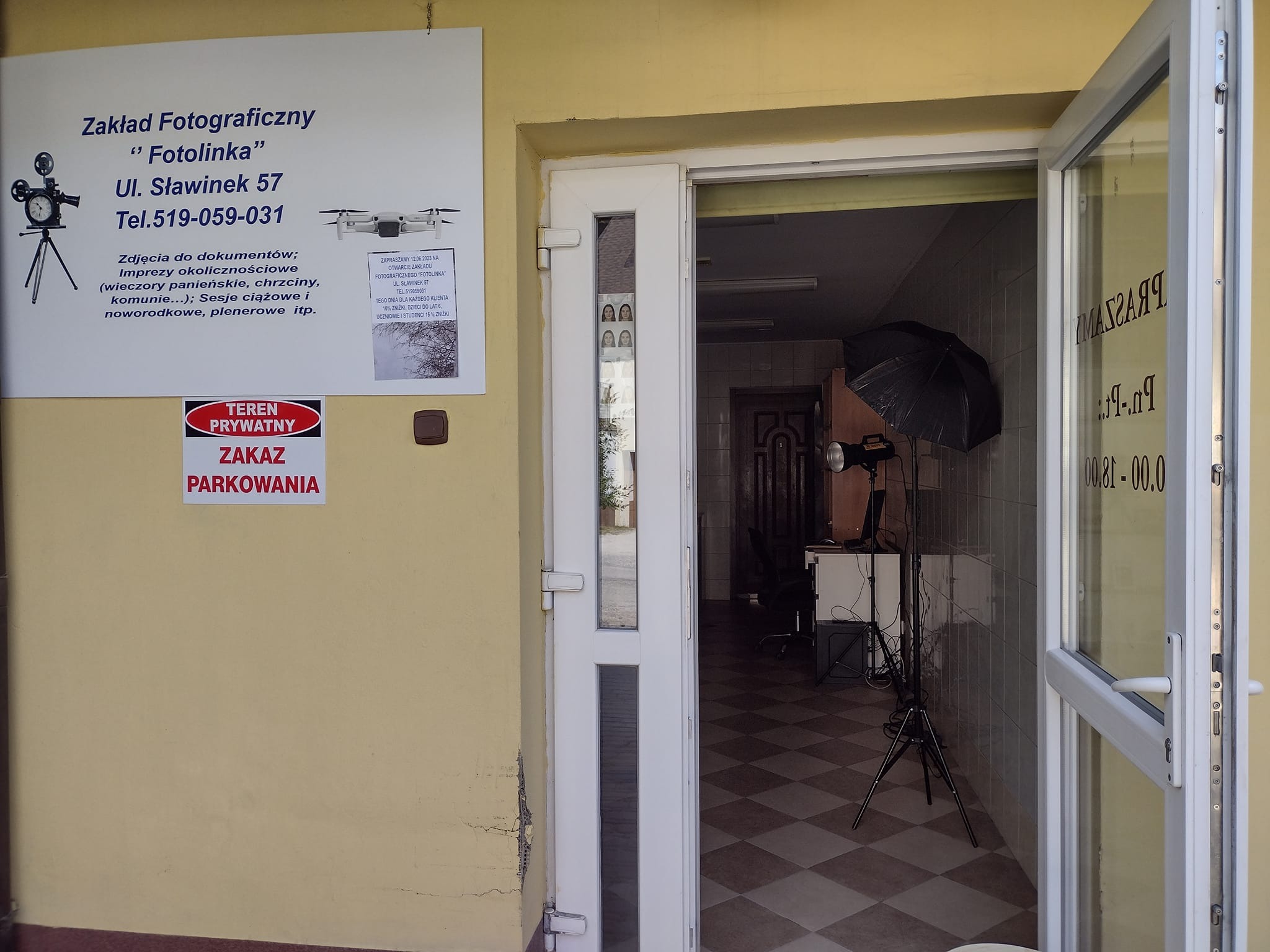 Wejście do zakładu fotograficznego 'Fotolinka' z widocznym szyldem informującym o ofercie: zdjęcia do dokumentów, imprezy okolicznościowe, sesje ciążowe i noworodkowe; w tle widoczny sprzęt studyjny.