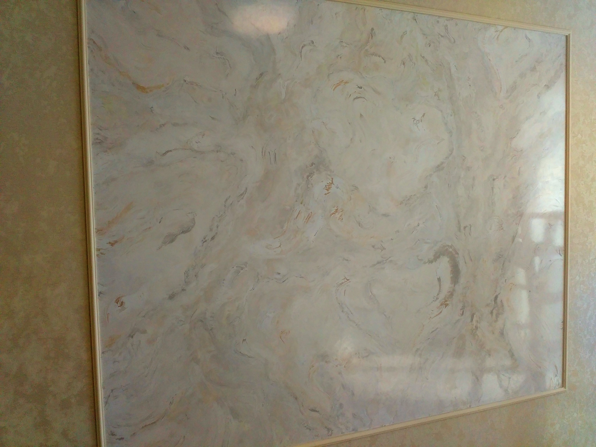 Ściana z efektem dekoracyjnym imitującym marmur w odcieniach beżu i bieli, obramowana listwą w kolorze kremowym.