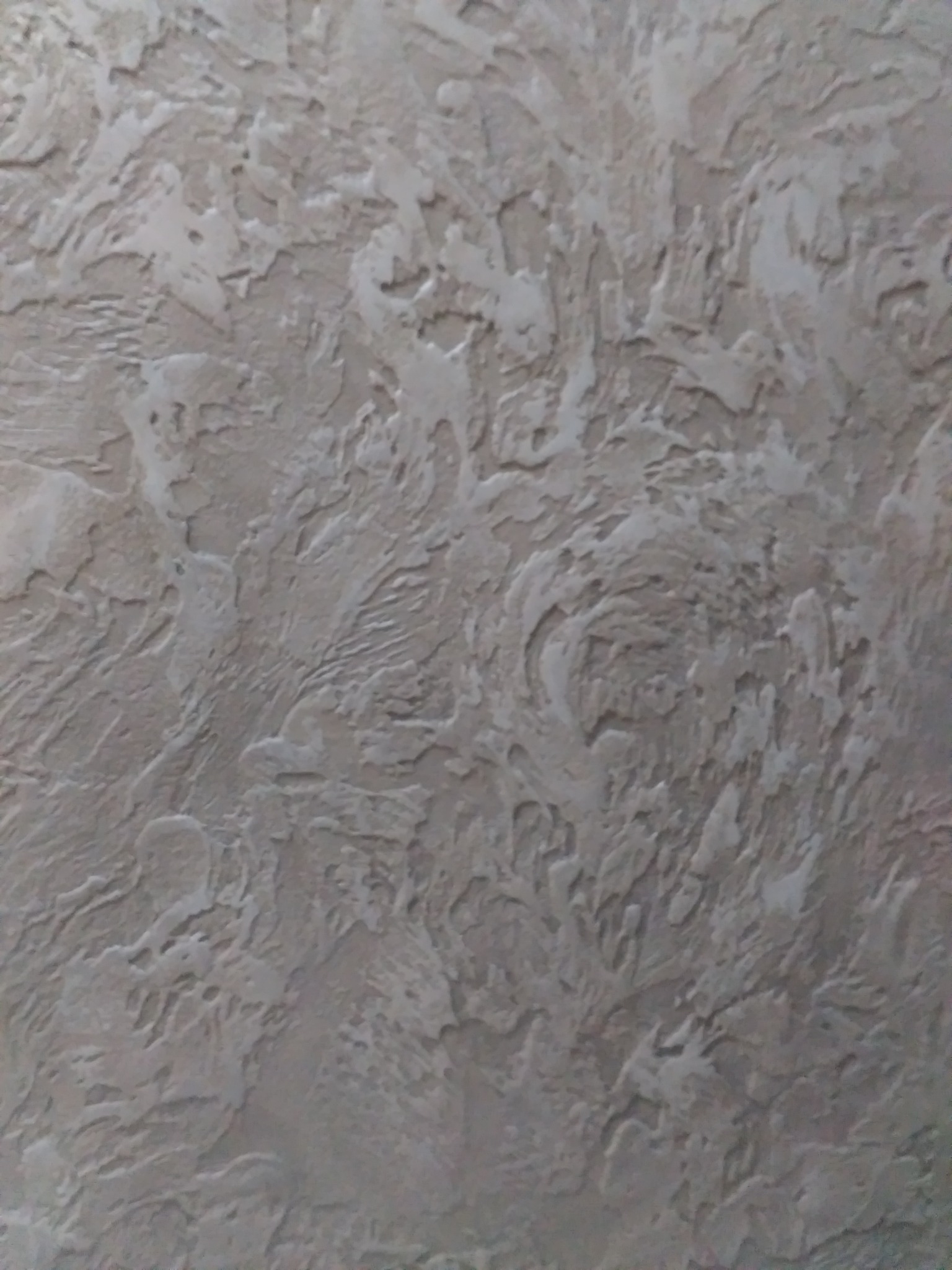 Szara ściana z dekoracyjną, nieregularną fakturą przypominającą wzburzone fale.