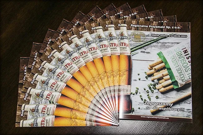 Stos ulotek reklamowych Regionalnych Przysmaków Sp. z o.o. z motywem butelki piwa Turys i przekąsek, oferta ważna do 28.02.2015.
