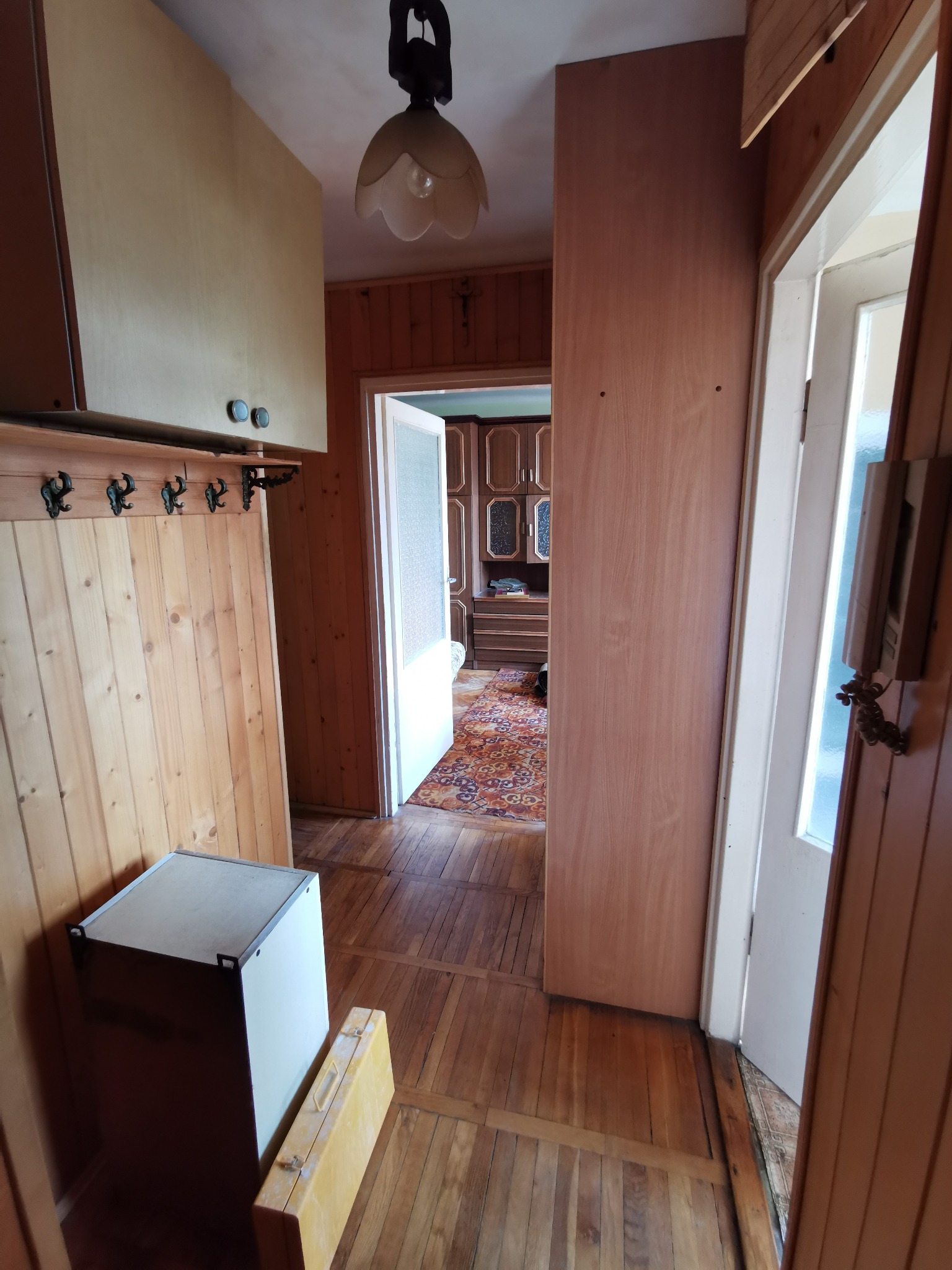 Korytarz w trakcie prac wykończeniowych: surowe drewniane panele ścienne, przygotowane do malowania, widoczna skrzynka narzędziowa i fragment podłogi z parkietu.