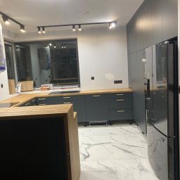 Wood-Mar - Nowoczesna kuchnia w odcieniach szarości z drewnianym blatem i marmurową podłogą, oświetlona reflektorami sufitowymi.