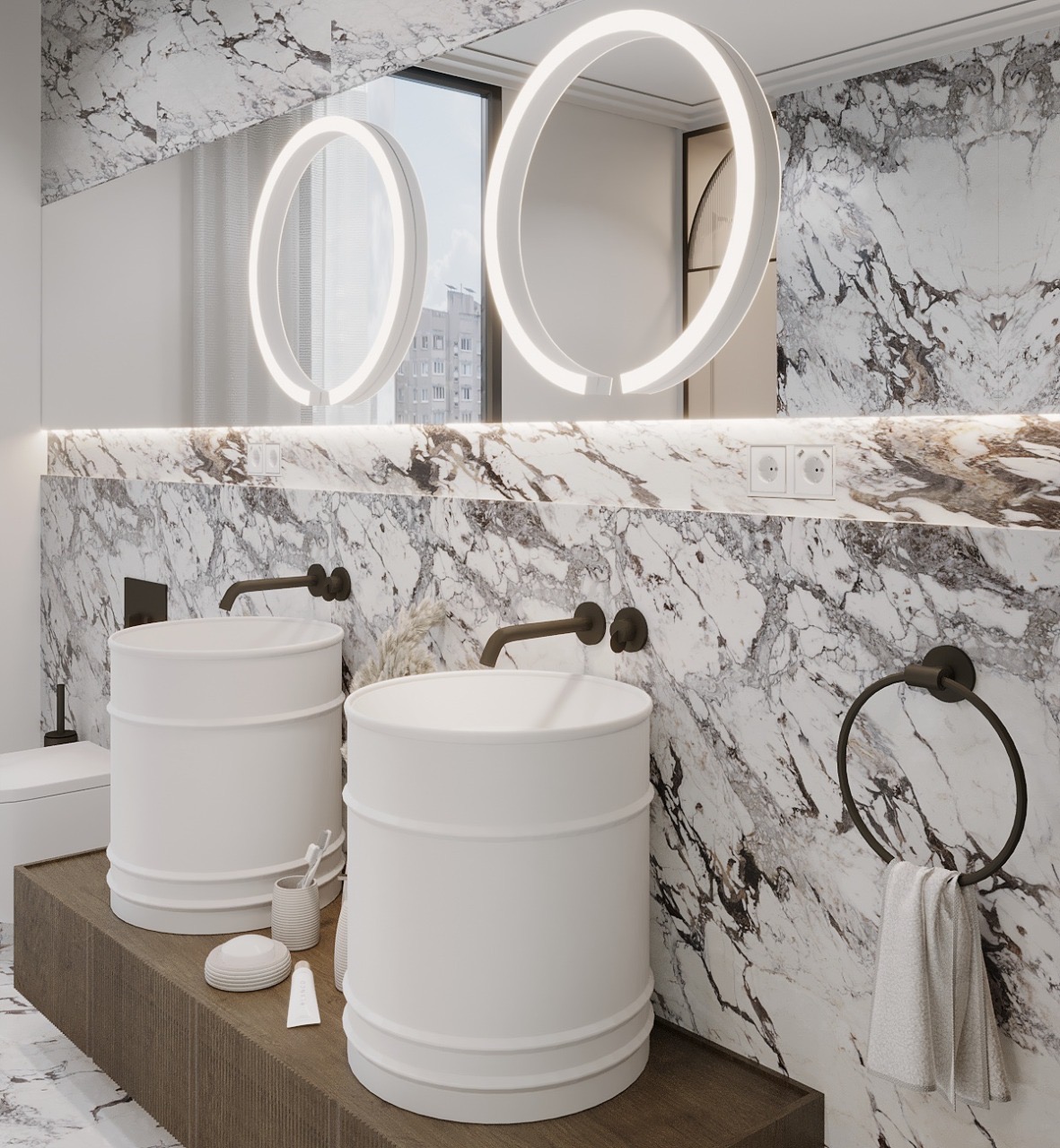 Nowoczesna łazienka z dwoma białymi umywalkami cylindrycznymi, czarnymi bateriami i okrągłymi lustrami podświetlanymi LED na tle marmurowej ściany.