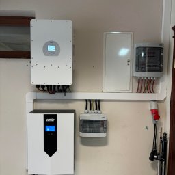 ARD-SUN Sławomir Jackowski - Kompletna instalacja fotowoltaiczna wewnątrz budynku: inwerter, magazyn energii Gen2, rozdzielnica i okablowanie. Widoczne elementy montażowe i złącza.