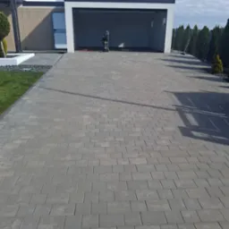 Kostka brukowa na podjeździe do garażu, widoczna myjka ciśnieniowa. Czysta powierzchnia, nowoczesny design.